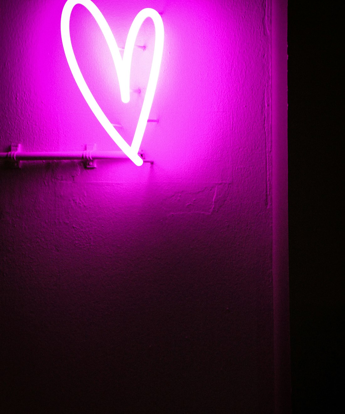 A neon heart glowing on a dark wall.